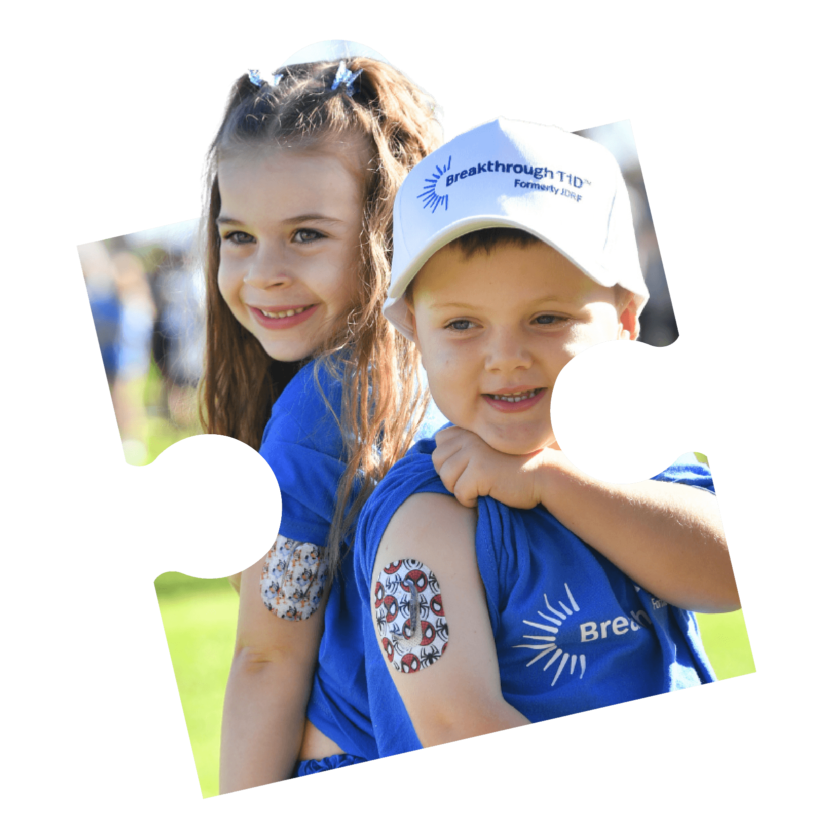 A boy and girl in Breakthrough T1D branded blue T-shirts smile together at an outdoor event.