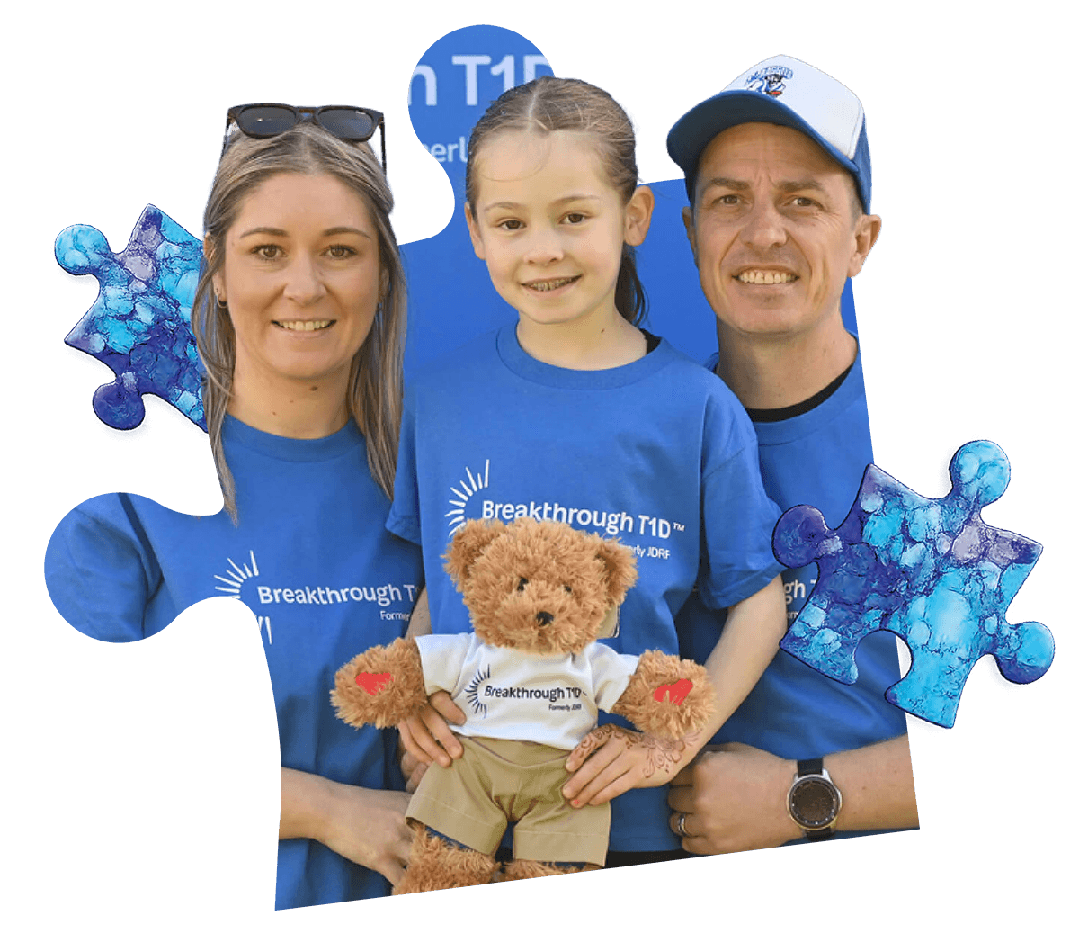 A little girl holding a Rufus teddy bear, with her parents around her.