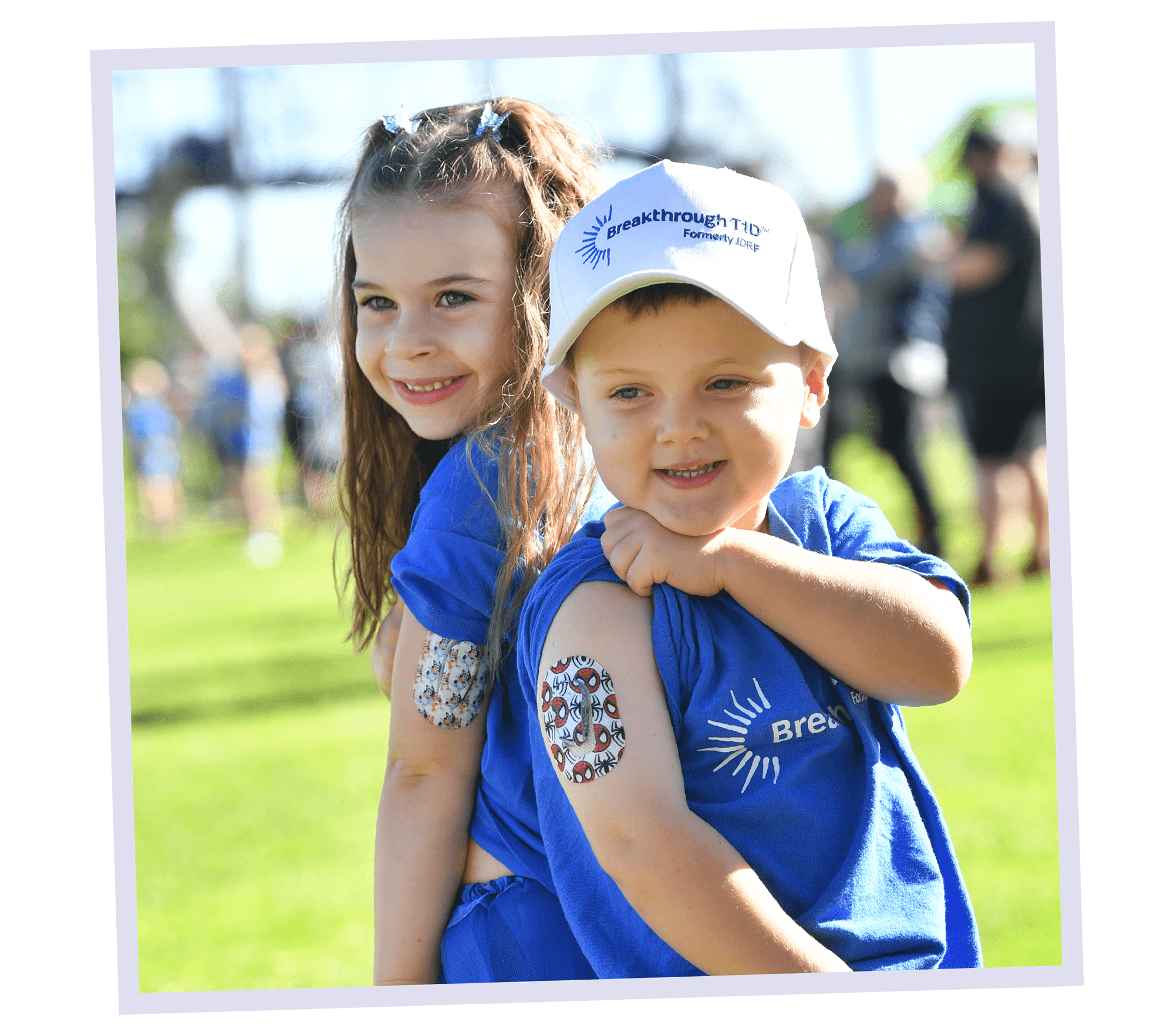 Fletcher and a little girl, smiling showing their CGM sensors. 